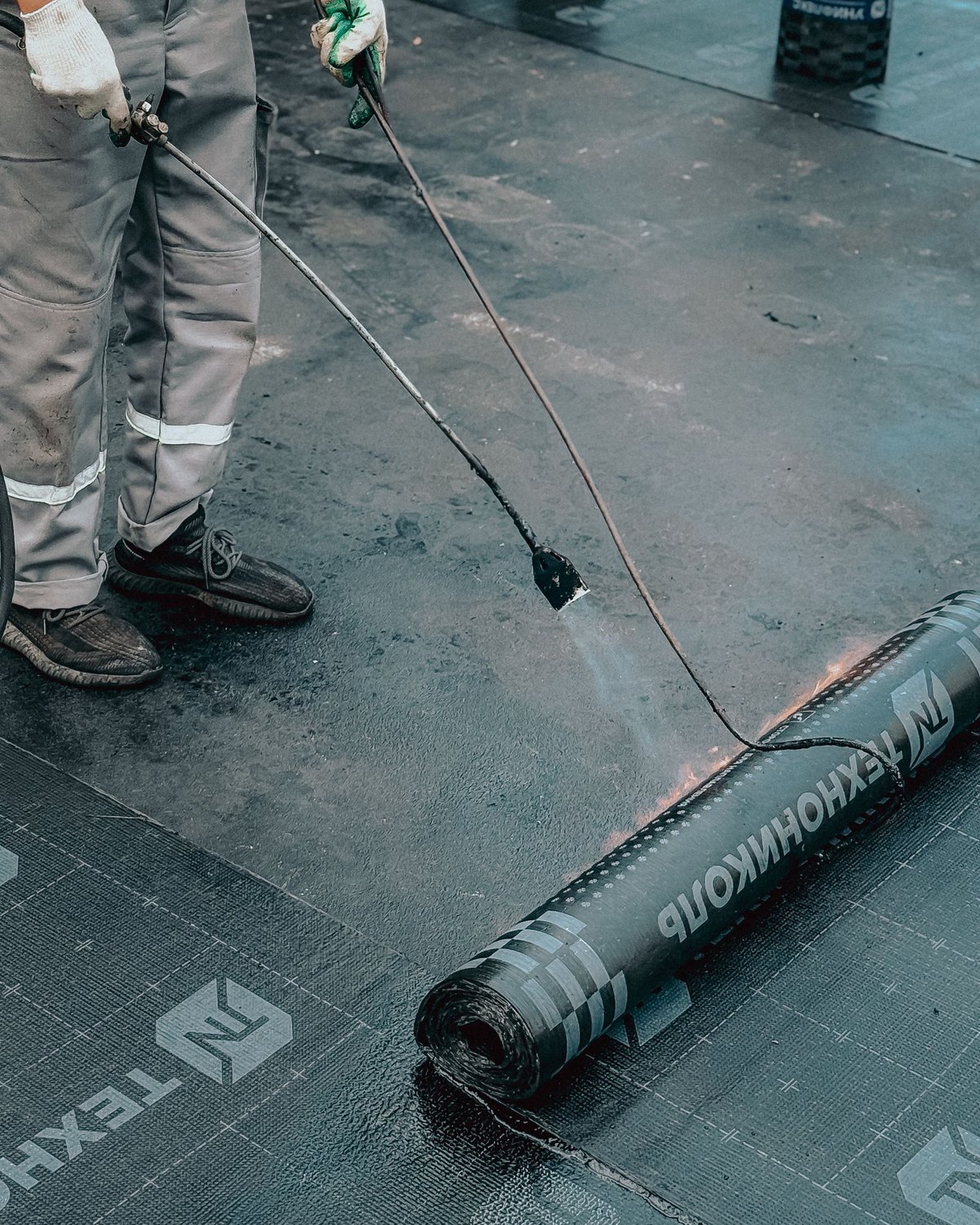 Roofer applying torch-on membrane to a flat roof